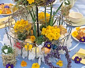 Wire stand with primulas, Easter eggs and feathers
