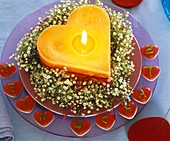 Gypsophila wreath around orange heart-shaped candle, with words