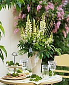 Vase of white lupins, tiered stand with biscuits