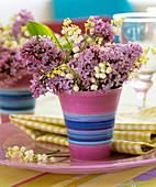 Flieder und Maiglöckchen in rosa-blau geringelter Vase