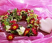 Wreath of primulas and hydrangea flowers, heart beside it