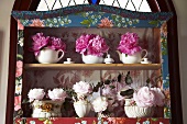 Peonies in various containers on shelves