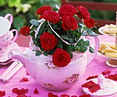 Rote Rosen in Teekanne auf Teetisch