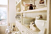 Crockery and ornaments on antique, white-painted kitchen dresser