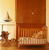 Cot in front of fitted wardrobe and wicker rocking horse