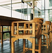 Rustikale Handwerkskunst in zeitgenössischem Gebäude - Holzstühle mit schmiedeeisernen Beschlägen um den alten Esstisch