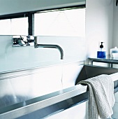 Wall-mounted taps and mirror above modern stainless steel sink