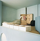 Schlafgalerie mit geöffnetem Kofferschrank vor raumhoher Schiebetür und aufgereihten Holzkisten