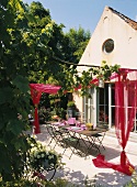 Kleines, altes Wohnhaus mit Bullauge im Giebel und Terrasse mit drapiertem, rotem Schleier über dem gedeckten Tisch