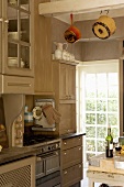 Detail of fitted, country-house-style kitchen with view of garden through lattice window