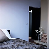 Bedroom in shades of blue and grey with ornaments on bedside table and view of door