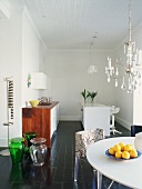 Verspielter Stilmix im offenen Wohnraum mit reduzierter Designerküche und Kronleuchter über dem Esstisch