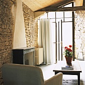 Rustikaler Wohnraum mit Natursteinwänden, Holzdecke und Glasfront