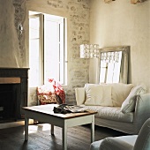 Wohnraum mit weiss übertünchter Natursteinwand und gemütlicher Couch mit großen Kissen