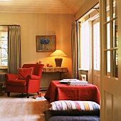Freundlicher Wohnraum mit gemütlicher Tischlampe, rotem Sessel und großen Bodenkissen