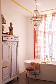 Bathroom with vintage cupboard, chandelier and free-standing bathtub