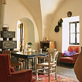 Wohnzimmer mit Deckengewölbe, Kaminofen, Durchgang mit Rundbogen, antikem Holztisch und goldbestickten Polstersesseln