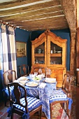 Blue dining room with set table, blue and white checked curtains and wood-beamed ceiling