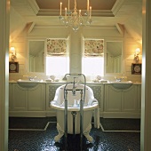 Stilvolles Badezimmer mit freistehender Badewanne, langem Waschtisch und integrierten Badezimmerfenstern mit Blumenrollos