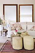 Zierkissen mit Rosenmotiv auf elegantem Sofa, davor fünf entrindete Baumstammtische