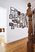 White hallway with large gallery of pictures on wall and foot of staircase