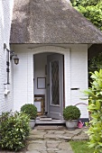 Open front door of brick house with thatched roof