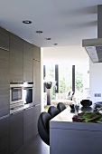 Moderne Küche mit Theke und Barhockern und mit Blick in den Wohnbereich