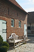 Facade of brick house with wooden bench and stone terrace