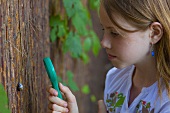 A girl observing a snail with a magnifying glass