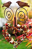 Heart-shaped wreath of rose hips & hydrangea flowers on ornamental post