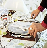 Hands placing cutlery at a place-setting