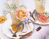 Place-settings with roses, gypsophila and Christmas spices