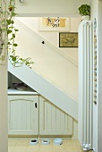 Blick auf weiße Treppe mit eingebautem Schrank in Nische und Hundenäpfe
