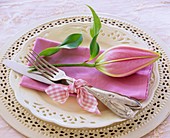 Pink napkin with lily bud on white plate