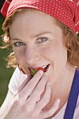 Young woman biting into strawberry