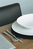 Nahaufnahme eines gedeckten Tisches mit weißem Teller, Schüssel und Edelstahlbesteck