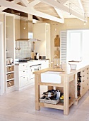Eine Küche mit Kochinsel aus massivem Holz unter offener Fachwerkskonstruktion
