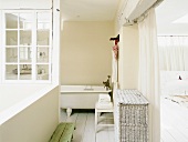 Blick in ein Badezimmer mit offener Fensterfront in den Innenhof und freistehender Badewanne