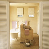 Mittig angeordneter Waschtisch aus Beton mit zwei Schalenwaschbecken und eine freistehende Badewanne dahinter