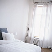 Doppelbett mit weißer Bettwäsche im hellen Schlafzimmer