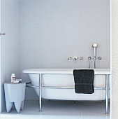Badewanne mit Metallhalterung in einem vollständig mit Mosaikfliesen gefliesten Badezimmer