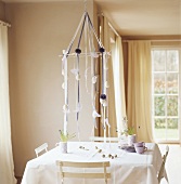 Suspended Easter decoration with Easter eggs above square table laid with white cloth