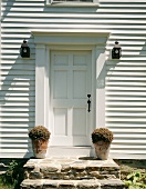 Hauseingang mit zur Haustür führenden Steinstufen und mit zwei Pflanzentöpfen aus Terrakotta