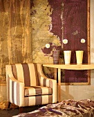 Gestreifter Sessel und Wandtisch mit Blumendekoration vor modernem Gemälde mit Holzrahmen