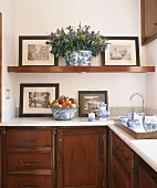 Nostalgic black and white photographs on kitchen shelf above blue and white tea service on wooden tray