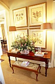 Holztisch und gepolsterte Sitznak vor Blumenbilder an der Wand