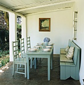 Gedeckter Holztisch und Sitzbank unter überdachte Terrasse