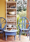 Blau lackierte Holzmöbel und Holzregal mit diversen Utensilien auf Veranda