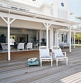 Strandhaus mit überdachte Terrasse und zwei Holzsessel mit identischen Kissen unter freiem Himmel