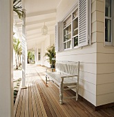 Weiß lackierte Holzbank auf Veranda mit Holzdielenboden